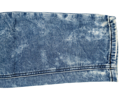 Close-up of blue acid-wash denim fabric sleeve with visible seam and hem, textured faded patterns.