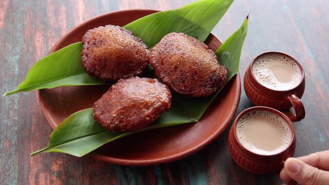 Neyyappam is a rice based kerala snack fried in ghee Famous Indian snack and Traditional kerala snack item. Crispy and tasty snack. Rice pancakes fried in ghee made of jaggery banana leaf side view