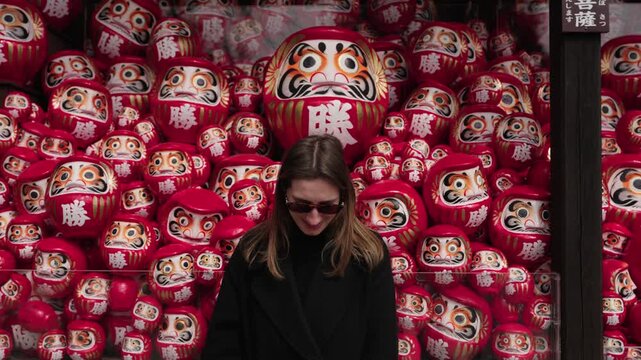 Woman Standing in Front of Daruma Dolls Wall Japan