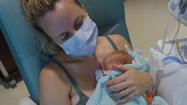 Young Mother Holds Premature Infant Baby in Neonatal Intensive Care Unit. Mask