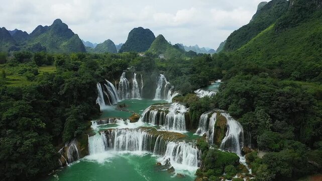 Aerial view of Ban Gioc Waterfall cascading through lush green mountains and dense forest, creating a dramatic natural landscape in northern Vietnam.