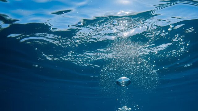 underwater bubbles rising under blue ocean surface from below