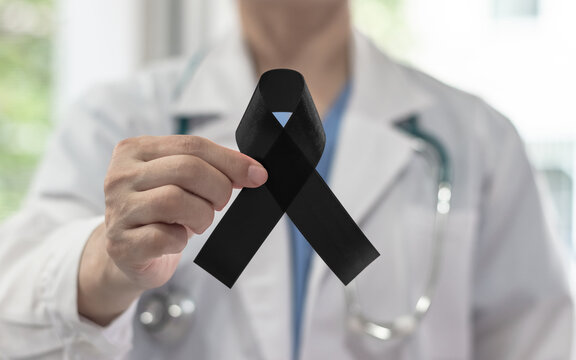 Black ribbon awareness in doctor's hand for Melanoma and skin cancer, Narcolepsy, Primary Biliary Cirrhosis (Cholangitis), Sleep Apnea Disorders and for mourning
