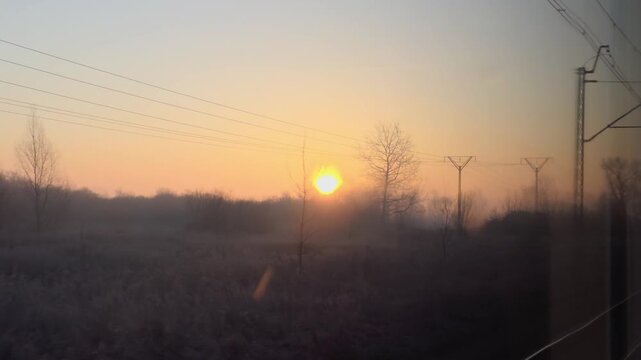 Sunset View from Train Window in Serene Landscape Covered in Mist