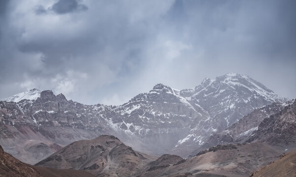 A rocky mountain ridge with snow against a cloudy sky in the Tien Shan Mountains in the Pamirs, a landscape for the background, a mountain panorama during rain