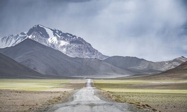 The Pamir Highway in the Tien Shan highlands of Tajikistan, a landscape with a road in the Pamirs, a road stretching into the distance against a backdrop of mountains