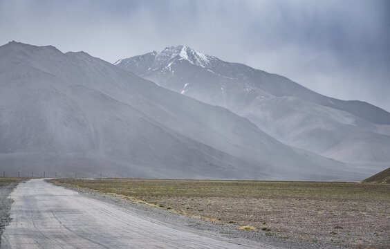 The Pamir Highway in the Tien Shan highlands of Tajikistan, a landscape with a road in the Pamirs, a road stretching into the distance against a backdrop of mountains