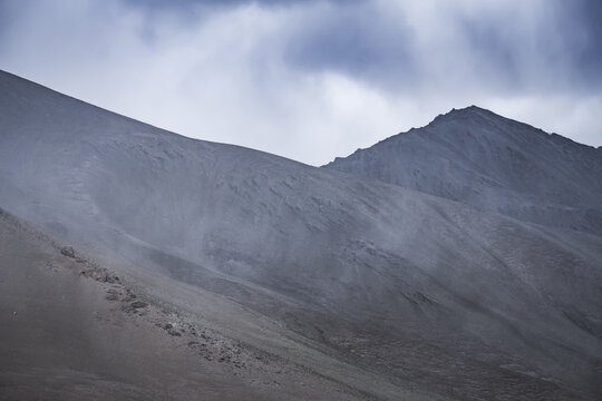 A rocky mountain ridge with snow against a cloudy sky in the Tien Shan Mountains in the Pamirs, a landscape for the background, a mountain panorama during rain