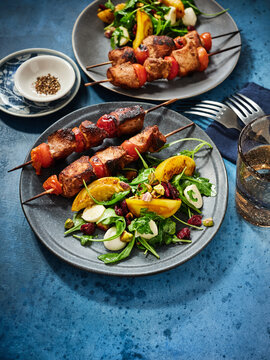 The image shows grilled chicken skewers served with a fresh salad featuring colorful vegetables. Perfect for restaurant menus, food blogs, and social media posts highlighting summer meals