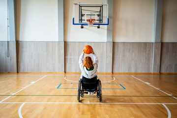 Wheelchair basketball player shooting ball towards hoop. © Halfpoint