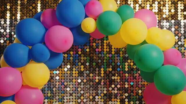 Colorful balloon arch with glittery sequin backdrop creating a festive party atmosphere for celebration
