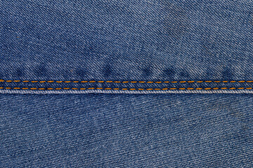 Blue denim fabric with visible seam and orange stitching detail