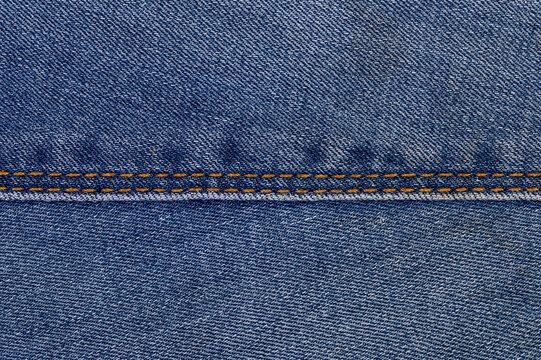 Blue denim fabric with visible seam and orange stitching detail