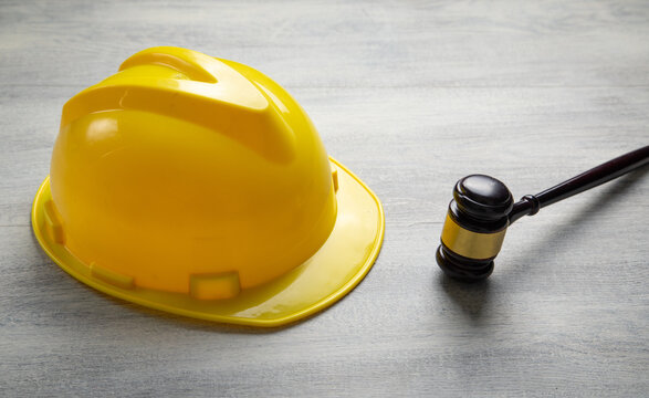 Yellow construction helmet and judge gavel on the table.
