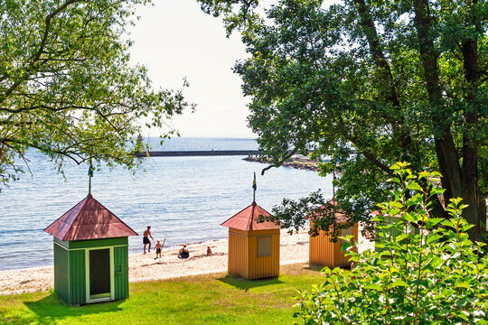 Colorful beach huts by the water with people enjoying a sunny summer day