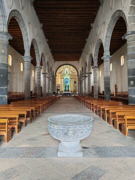 Interior de iglesia colonial hist&oacute;rica con pila bautismal y bancas.