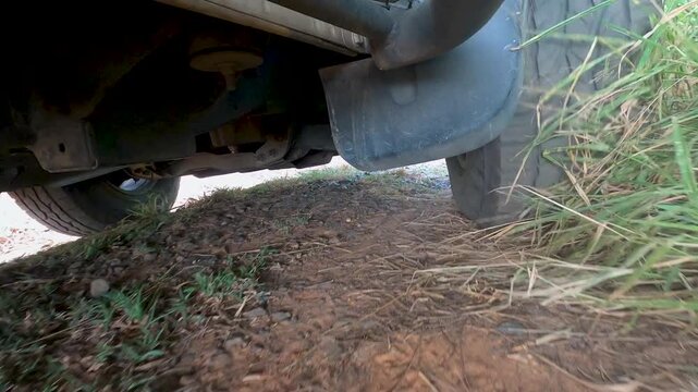 Low angle close up of a car tire driving on a dusty gravel road in rural countryside, capturing texture, motion and rugged travel atmosphere for road trip and transportation concepts