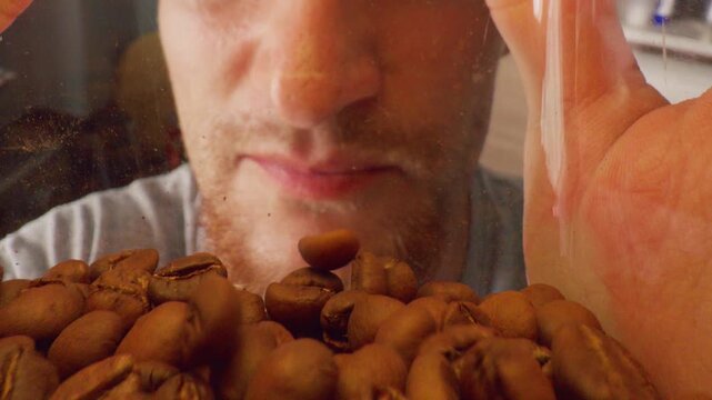 Man Tilting Coffee Bean Container Toward Himself Viewed from Inside as Beans Slide Down in Wide Angle with Strong Overhead Light, Coffee Storage Concept