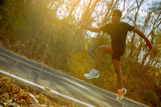 Silhouette of young man running sprinting on road. Fit runner fitness runner during outdoor workout with sunset background