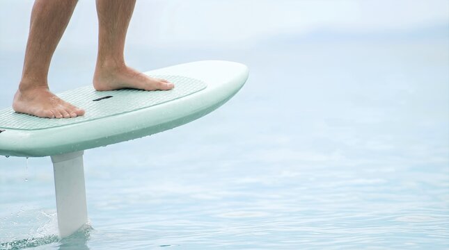 E-foil surfboard with rider standing on the water, showcasing high-tech design and hydrofoil technology in a serene aquatic environment