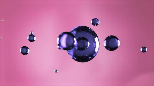 Shiny blue spherical bubbles or liquid droplets floating against a soft pink colored backdrop, providing a pleasing color contrast for modern motion design.