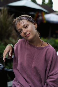 Close up portrait of young woman with wet hair smiling softly outdoors