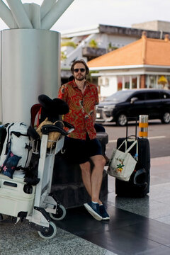 Stylish man tourist with overpacked luggage waiting outside airport