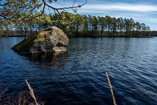 Big stone in calm lake with blue sky