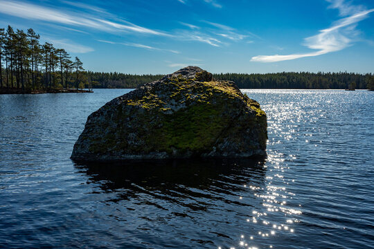 Big stone in calm lake with blue sky