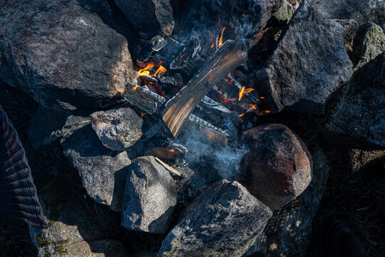 Grill grate beside small camp fire with stones around