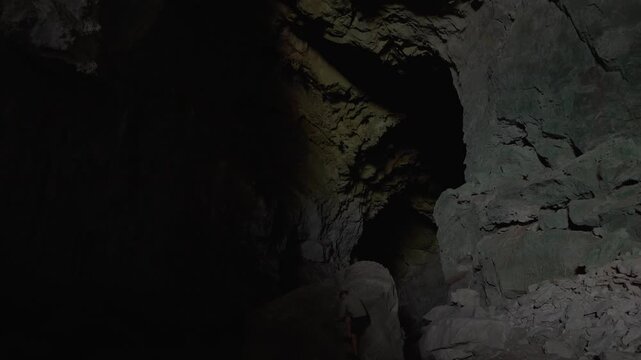 Static shot of the large Nam Non cave as a man climbs up a vantage point to have a look at the cave walls.
