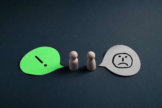 Miscommunication concept with wooden figures and exclamation mark and sad face speech bubbles