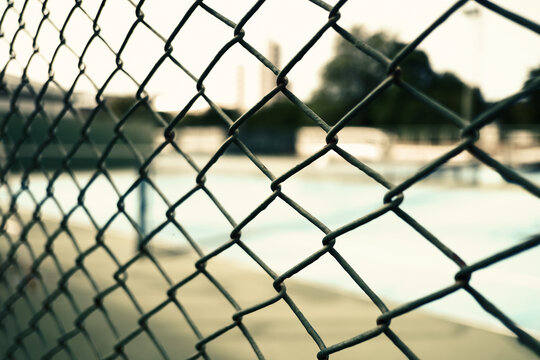 Steel wire mesh fence at an outdoor sports court. Concept of boundary, security, and athletic background.