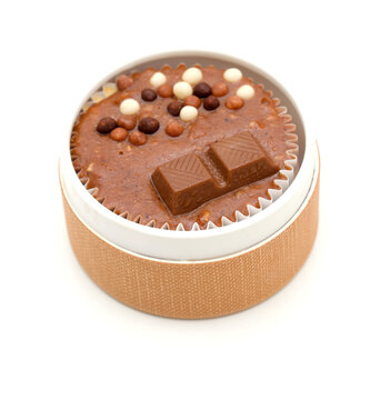 an individual chocolate cheesecake with chocolate drops and pieces at the top in a small round container
