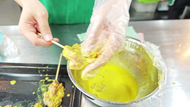 Traditional Thai pork satay skewers with yellow turmeric marinade on a metal tray.