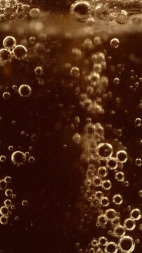 Golden bubbles rising in carbonated liquid for refreshment and beverage advertisement background