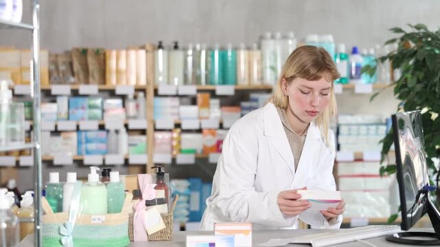 Young female pharmacist working with computer in pharmacy