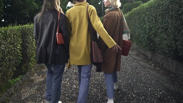Three women walking on a garden path.
