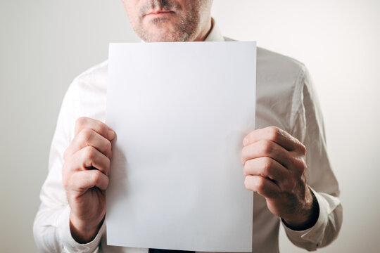 Businessman holding a blank white paper sheet, mockup for notices, contracts, warnings, announcements and resumes
