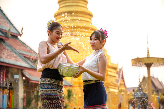 Thai women in traditional Northern Thai clothing holding water bowl splashing water to eacher celebrate Songkran in Chiangmai temple