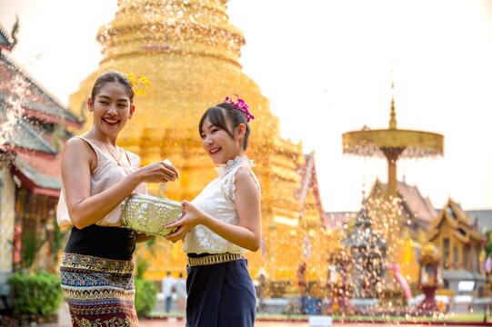 Thai women in traditional Northern Thai clothing holding water bowl splashing water to eacher celebrate Songkran in Chiangmai temple