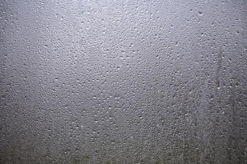 Obraz premium Closeup Of Water Droplets And Condensation On Glass Window With Gray Textured Surface