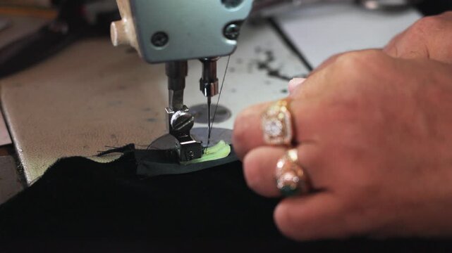 Slow Motion close-up of a sewing machine stitching fabric for a traditional songkok in Malaysia. Skilled craftsmanship and precise hand guidance highlight cultural garment production.