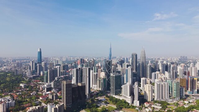 Wide drone shot of Kuala Lumpur skyline featuring KLCC dense high-rise buildings, modern infrastructure, and vibrant urban landscape under clear daylight. UHD.