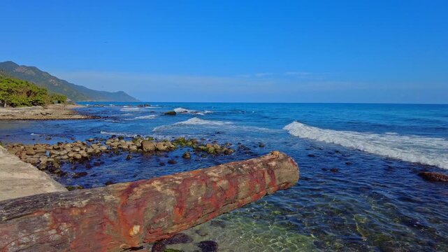 A static view of a deteriorated heritage cannon facing the boardwalk in Choroni, Aragua, Venezuela; the Venezuelan coastline in the morning with the calm Caribbean Sea
