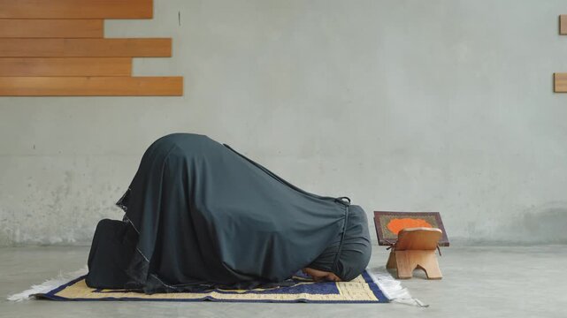 Muslim woman performing prayer alone with Quran placed on a wooden stand, representing devotion, solitude, and spiritual connection.
