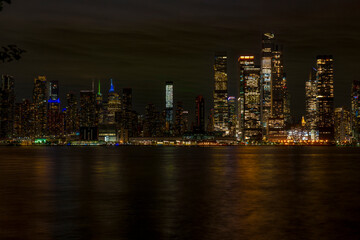 Obraz premium New York City skyline at night with illuminated skyscrapers and reflections