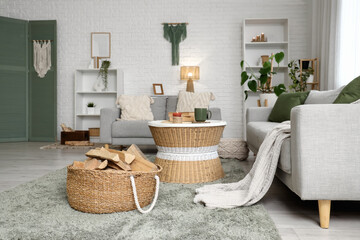 Obraz premium Interior of living room with sofas, shelving units, coffee table and firewood in wicker basket