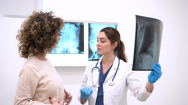 Chest X-ray Analysis. Female doctor in white coat explaining lung radiograph to a young woman in a modern hospital office. Diagnostic radiology and healthcare concept. Medical exam and results.