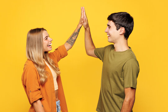 Young fun happy couple two friends family man woman wear casual clothes together meeting together greet giving high five clapping hands folded isolated on pastel plain light yellow color background
